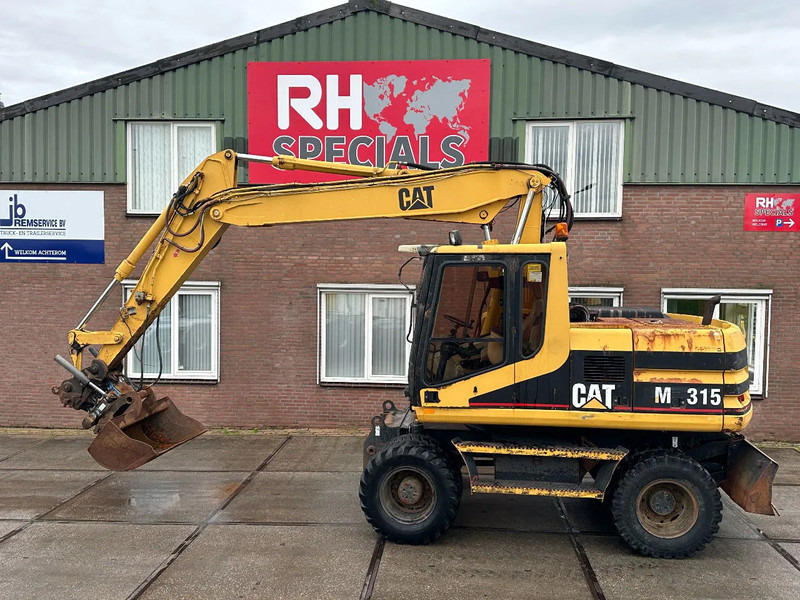 Caterpillar M315 +ROTO CE - حفارة دولاب: صورة 1 Caterpillar M315 +ROTO CE - حفارة دولاب: صورة 1