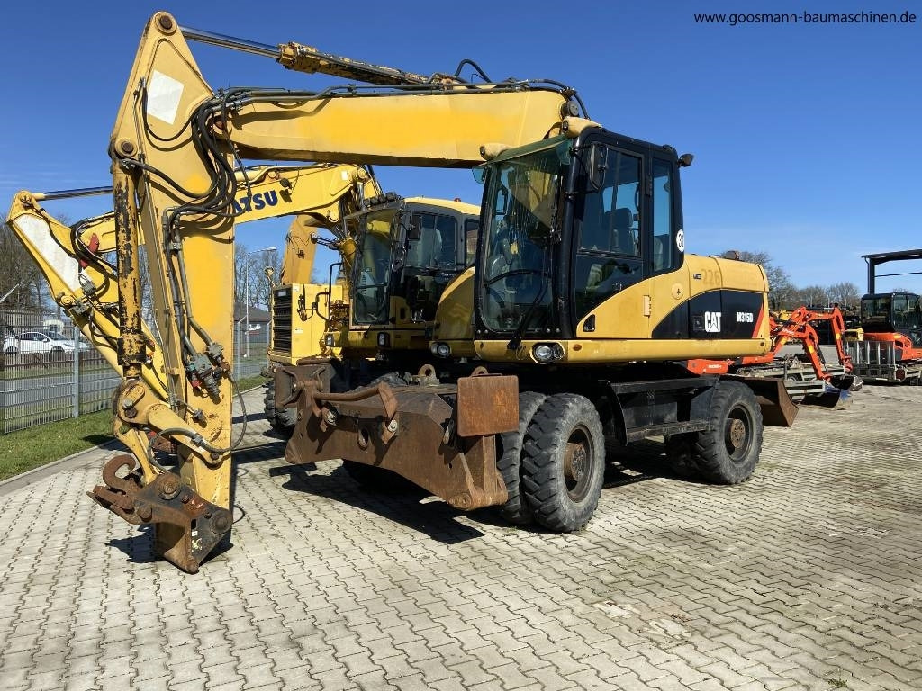CAT M 315D - حفارة دولاب: صورة 1 CAT M 315D - حفارة دولاب: صورة 1